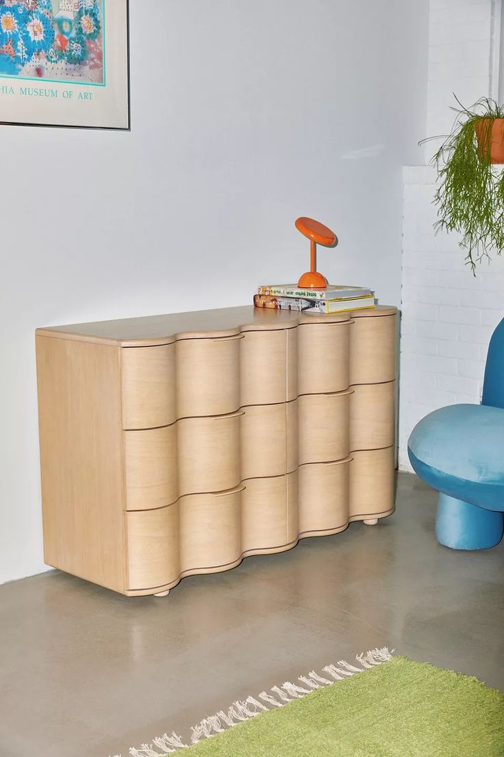 a room with a blue chair and a wooden dresser in it's center area