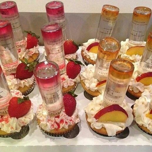 a table topped with lots of cupcakes covered in frosting and strawberries