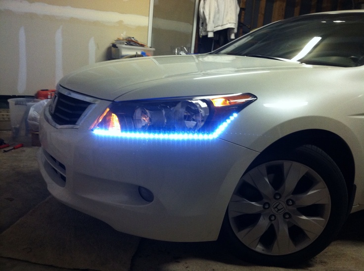 a white car with blue lights is parked in a garage next to a man standing on the stairs