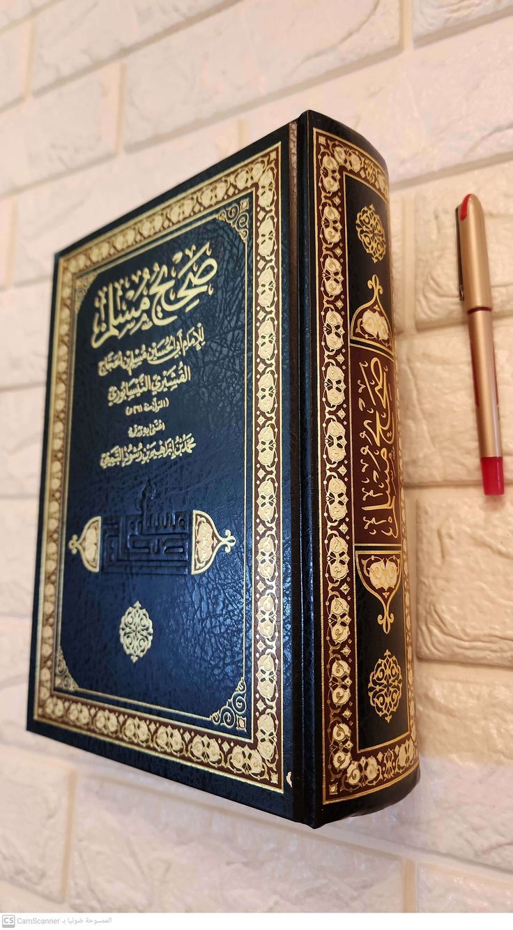 a blue book with arabic writing on it and a red pen hanging from the wall