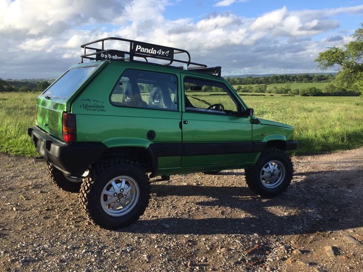 a green pick up truck parked on top of a dirt road