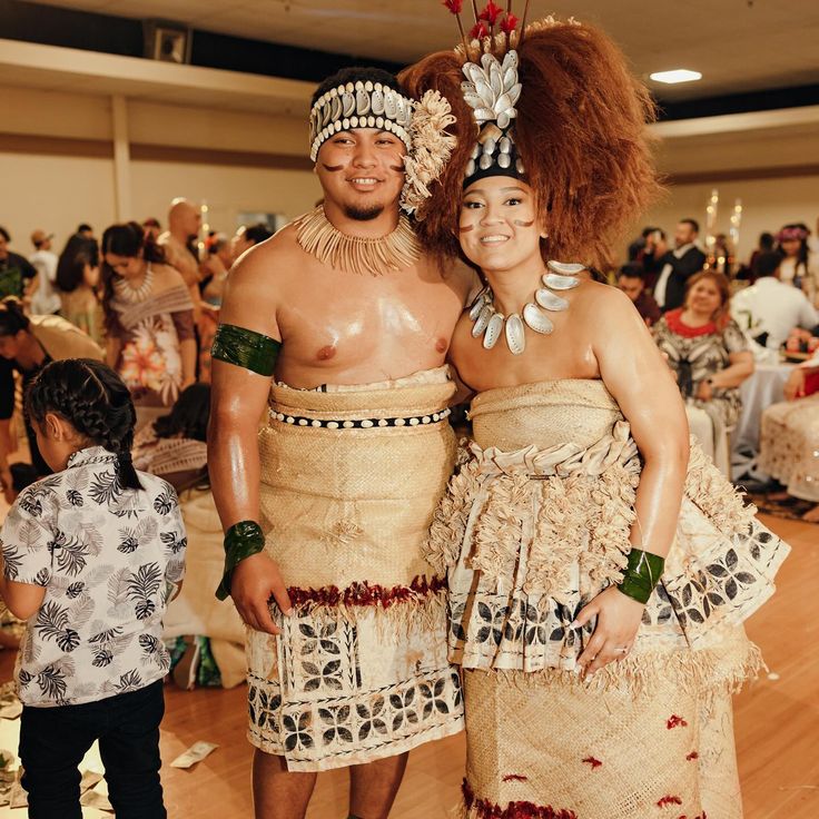 two people dressed in costumes standing next to each other on a wooden floor with lots of people around them