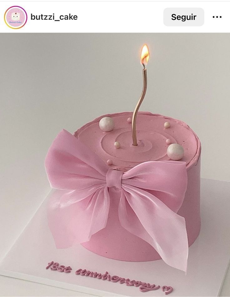 a pink birthday cake with a single candle