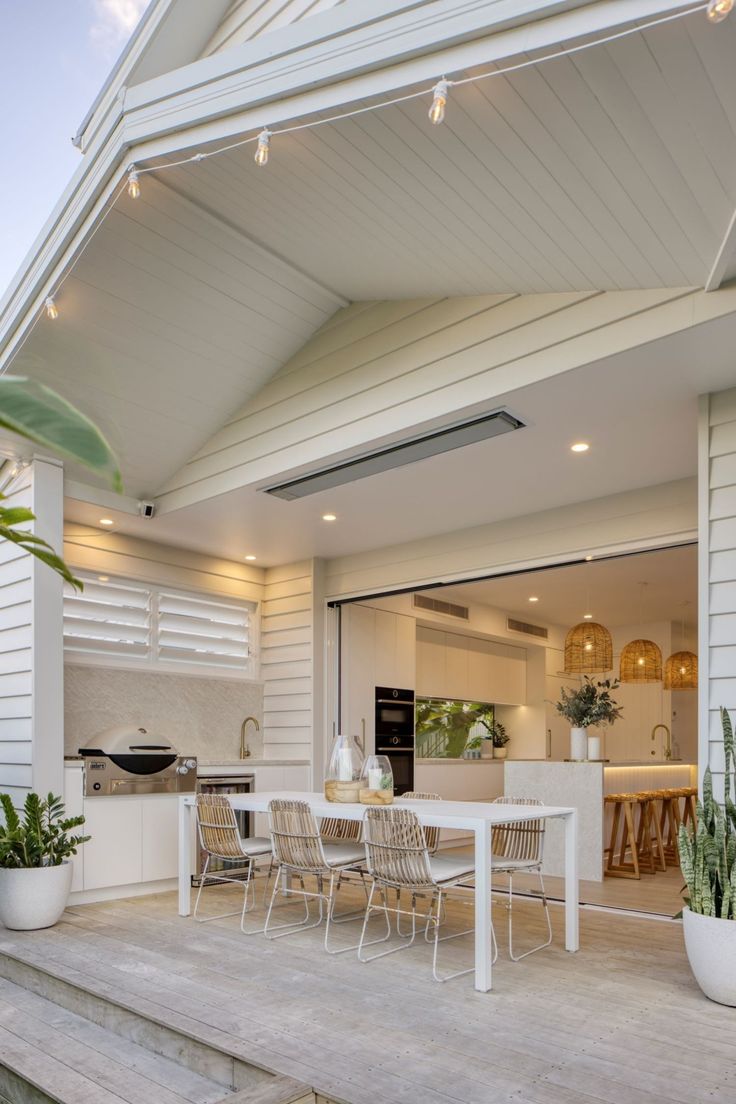 an outdoor kitchen and dining area on a deck with potted plants in the foreground