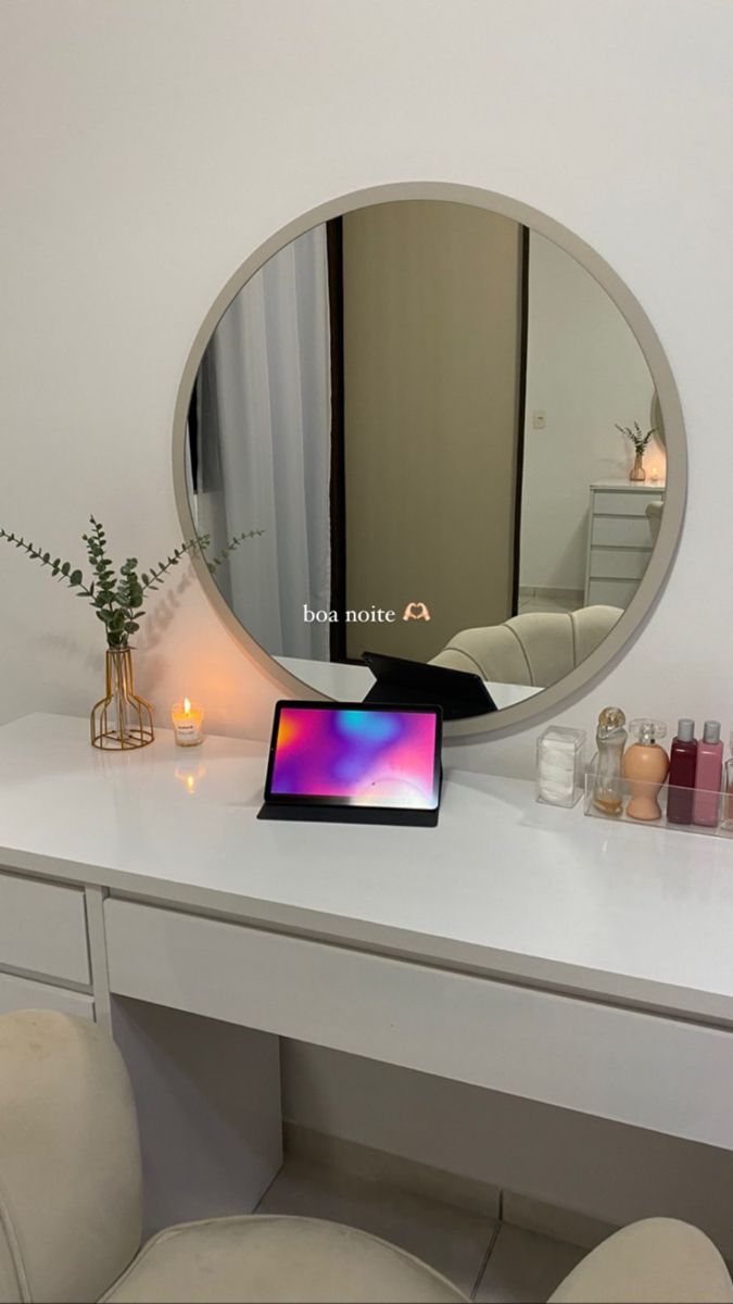 a laptop computer sitting on top of a white desk in front of a round mirror