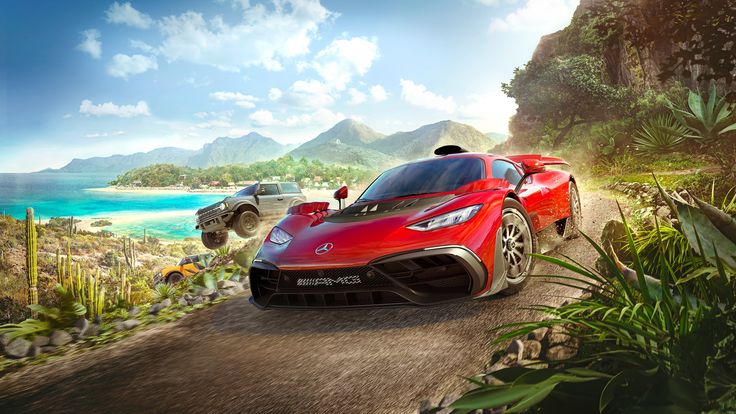 a red sports car driving down a dirt road next to the ocean with people standing on top of it