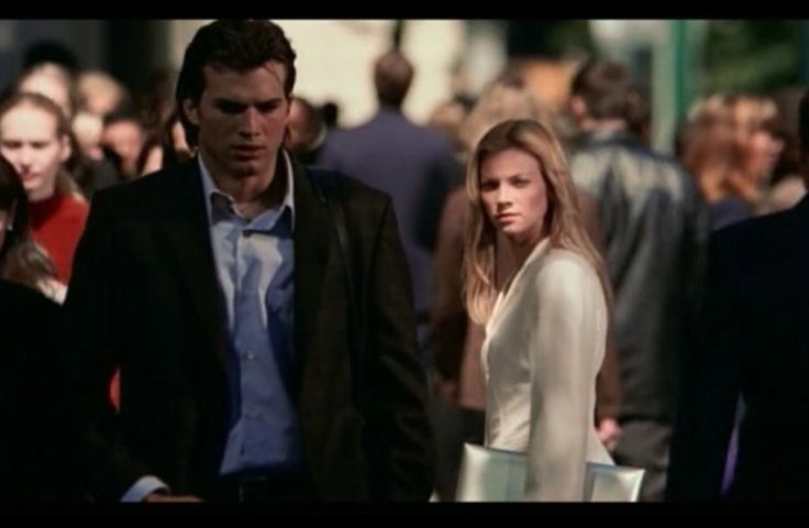 a man and woman are walking down the street in front of a crowd of people