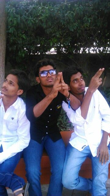 three men are sitting on a bench and posing for the camera with their hands in the air