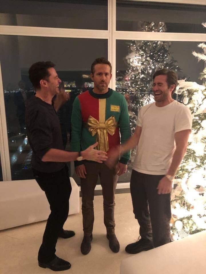 three men standing next to each other in front of a christmas tree