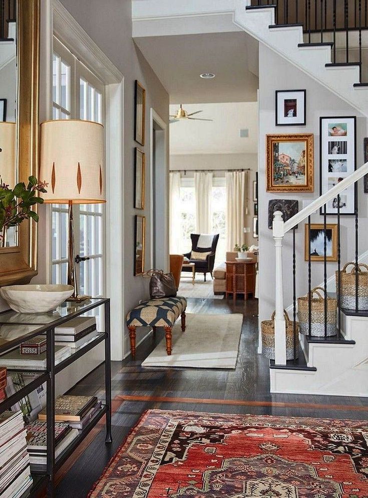 an entry way with stairs, rugs and pictures on the wall in front of it