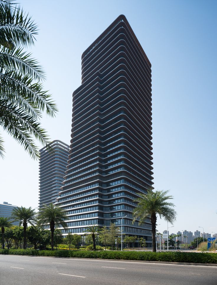 two tall buildings next to each other on a street with palm trees in the foreground