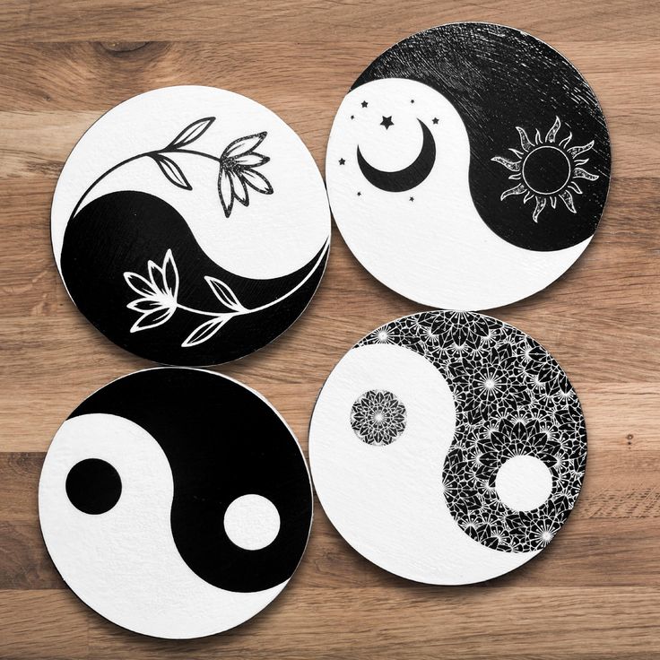 four black and white yin - yang coasters sitting on top of a wooden table