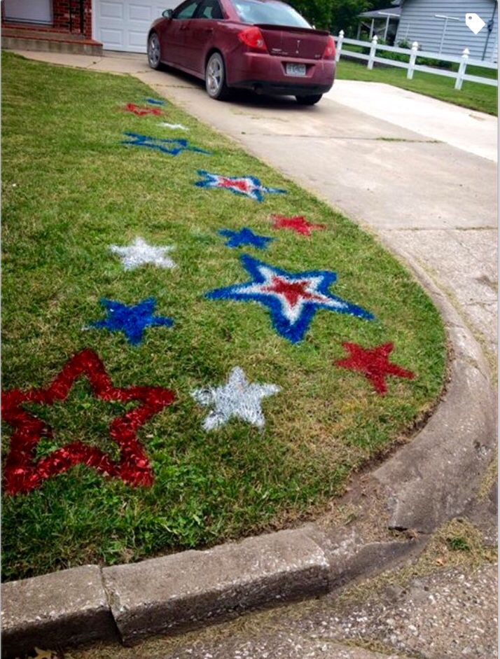 a red car parked in front of a house with stars painted on the grass next to it