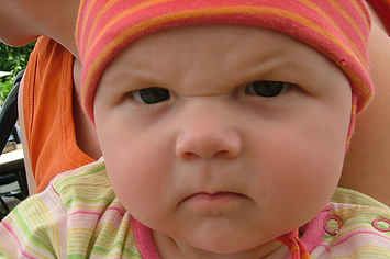 a baby is wearing a pink hat and looking at the camera with words written on it