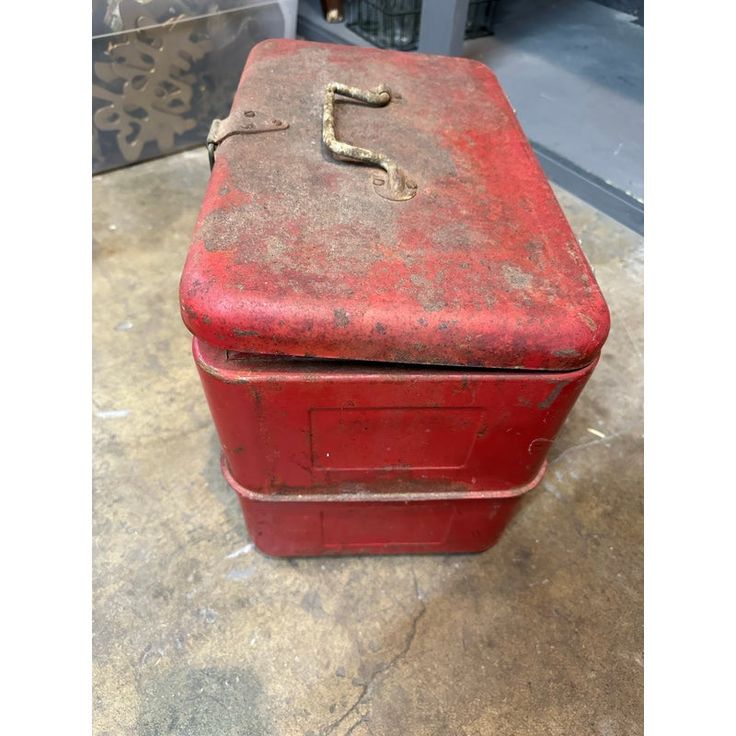 an old red metal box sitting on the ground