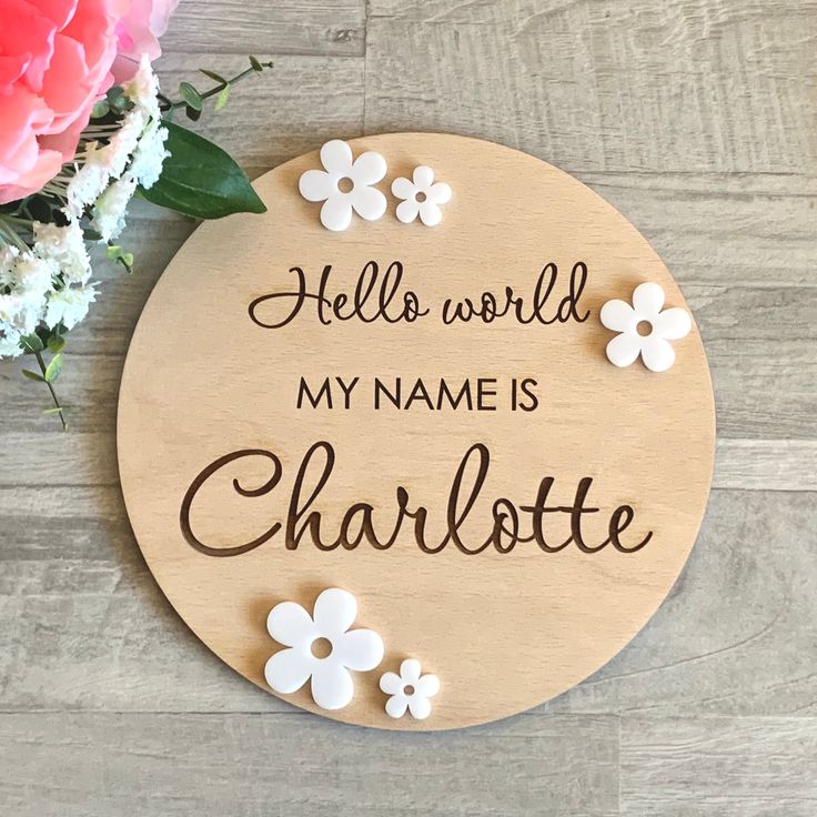 a wooden sign that says hello world, my name is charlotte with flowers on it