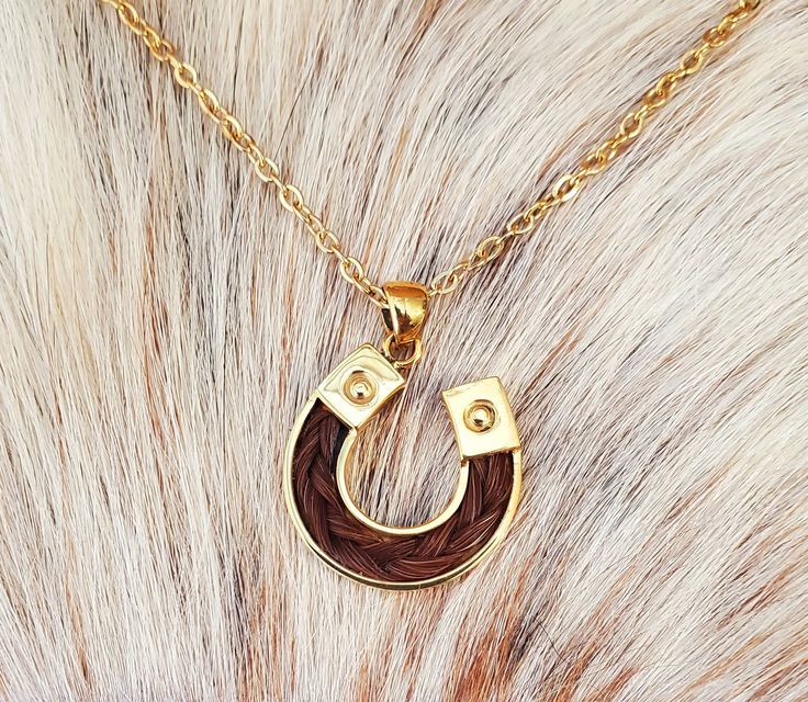 24K Gold overlay 925 Sterling Silver Horse Hair Horseshoe Pendant Necklace.  Pendant is approximately 25mm x 25mm and includes braided horse hair.  This beautiful pendants can be made with your horse's hair or we can make it with our stock horse hair.   Add engraving to your Pendant:  https://blueeyesdesignshb.etsy.com/listing/1769925811 Add a Custom Engraved Wood Gift Box: https://blueeyesdesignshb.etsy.com/listing/1750883342 Some of my other pendants can also be Gold Plated - Just ask! Pendants include a Gold Plated Stainless Steel Necklace Chain that is 18" long See my other horse hair keepsakes:  https://www.etsy.com/shop/BlueEyesDesignsHB?ref=seller-platform-mcnav§ion_id=43697745 -If you want something custom made, email me at BlueEyesDesignsHB@gmail.com -I will send an Etsy message w Wood Engraved Gifts, Stock Horse, Hair Keepsake, Horse Hair Jewelry, Beautiful Pendants, Wood Gift Box, Boot Bracelet, Horseshoe Pendant, Silver Horse