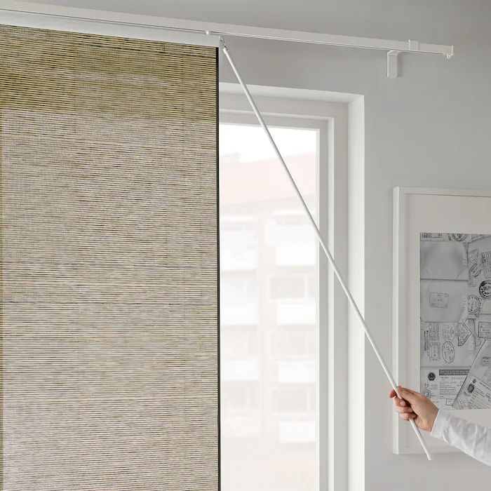 a person holding a string in front of a window with blinds on the outside and inside