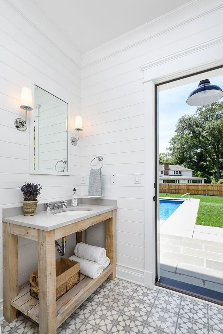 a bathroom with a sink, mirror and sliding glass door leading to a pool area