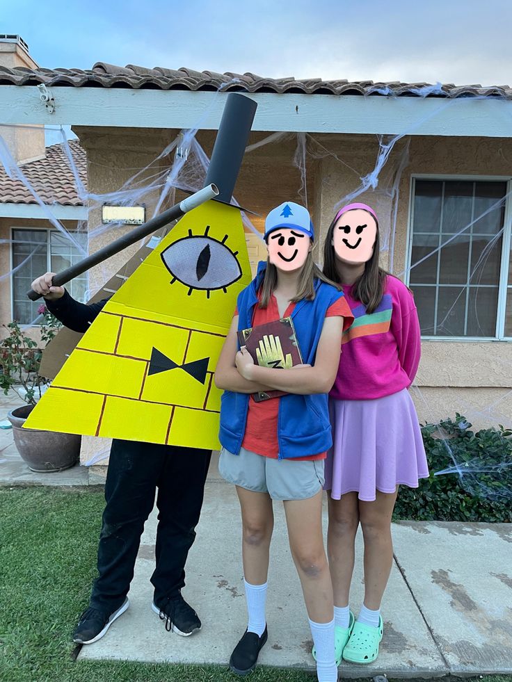 two girls and a man are standing in front of a house wearing paper mache costumes