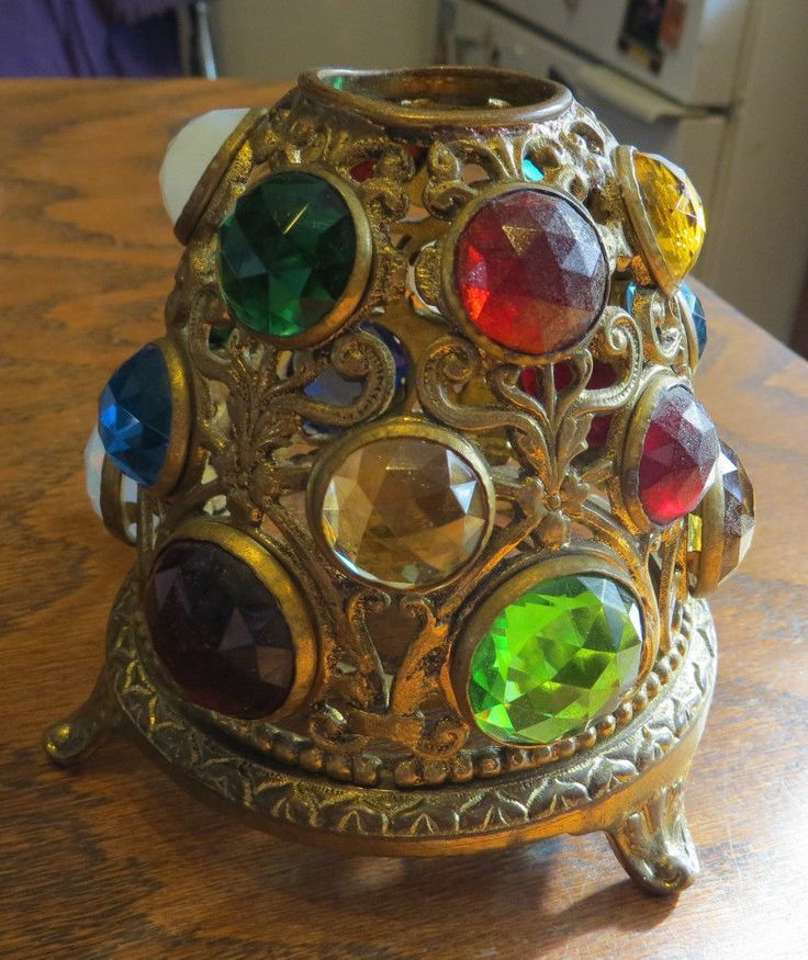 a close up of a metal object on a wooden table with many different colored stones