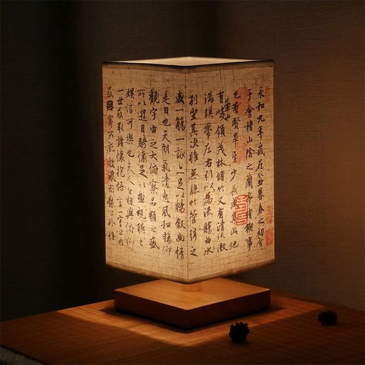 a lamp that is sitting on top of a wooden table in front of a wall