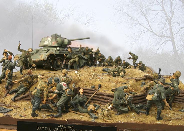 a group of toy soldiers on top of a hill with a tank in the background