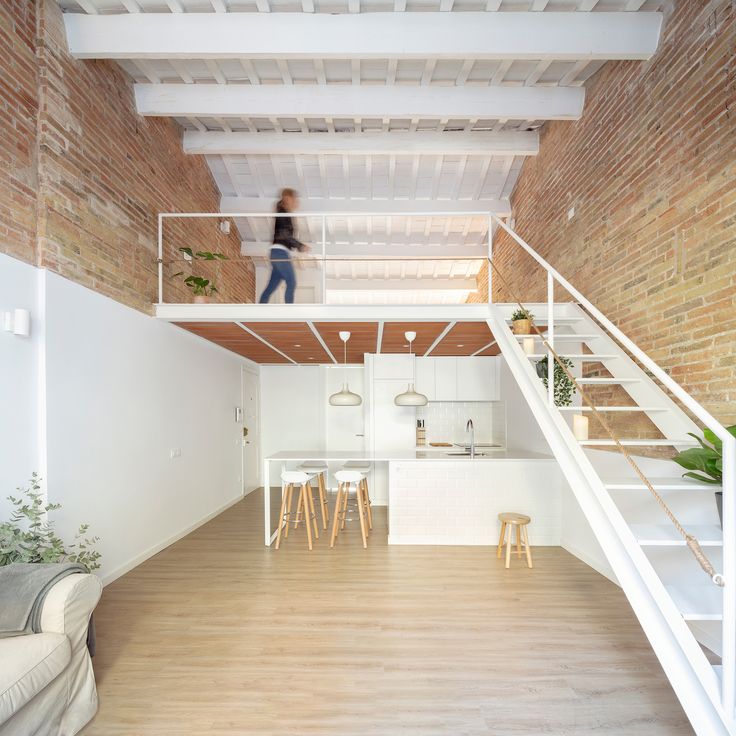 a woman is walking up the stairs in a loft style apartment with white walls and wood flooring