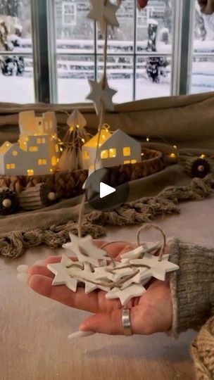 a person is holding some paper stars in front of a christmas scene with houses and trees