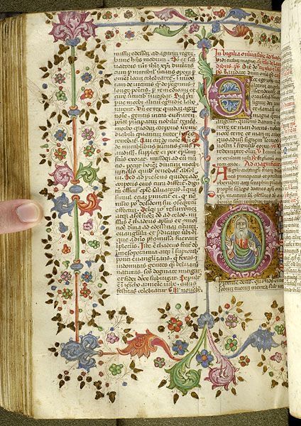 an open book with ornate designs and writing on the pages is being held by a person's hand