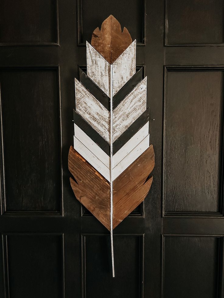 a wooden arrow hanging on the side of a black door with white and brown stripes