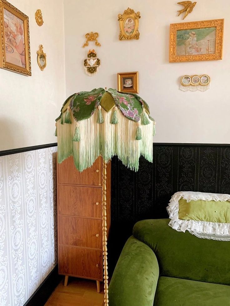 a green couch sitting next to a wooden cabinet in a room with pictures on the wall