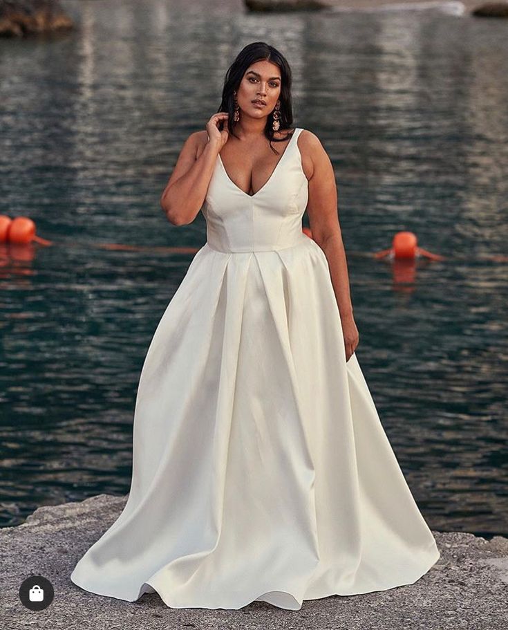 a woman in a white dress standing by the water