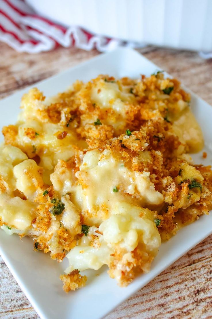 a white plate topped with macaroni and cheese on top of a wooden table