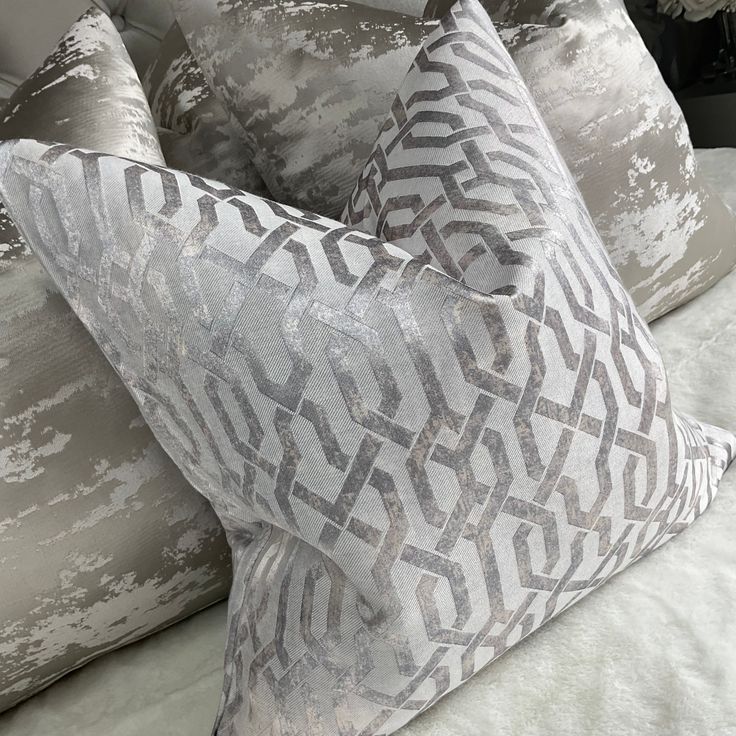 two decorative pillows sitting on top of a bed