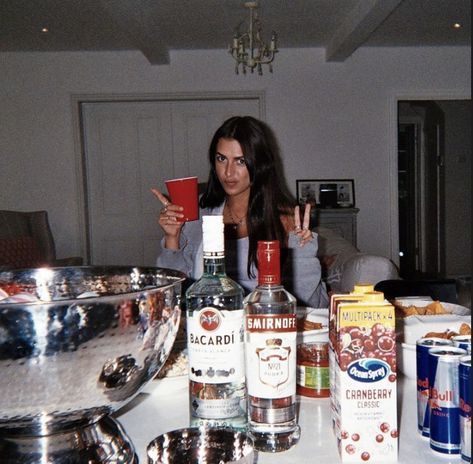 a woman sitting at a kitchen counter holding up a red cup in front of her