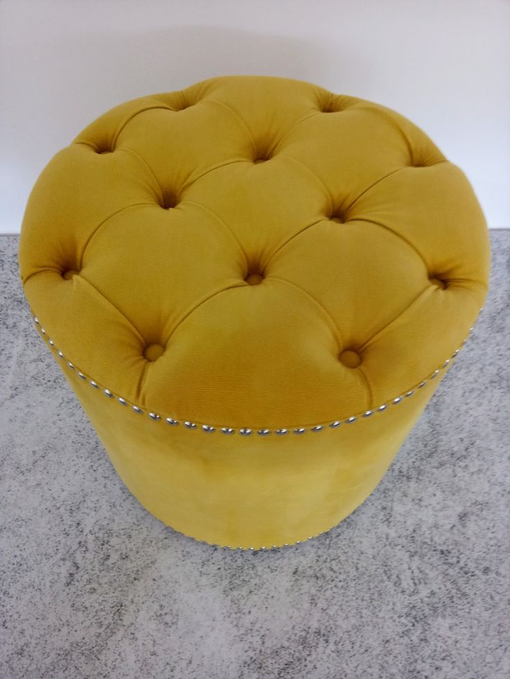 a yellow ottoman sitting on top of a gray floor