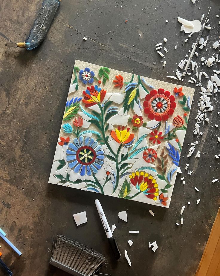 an artistically painted tile is being worked on with tools and shaving knifes