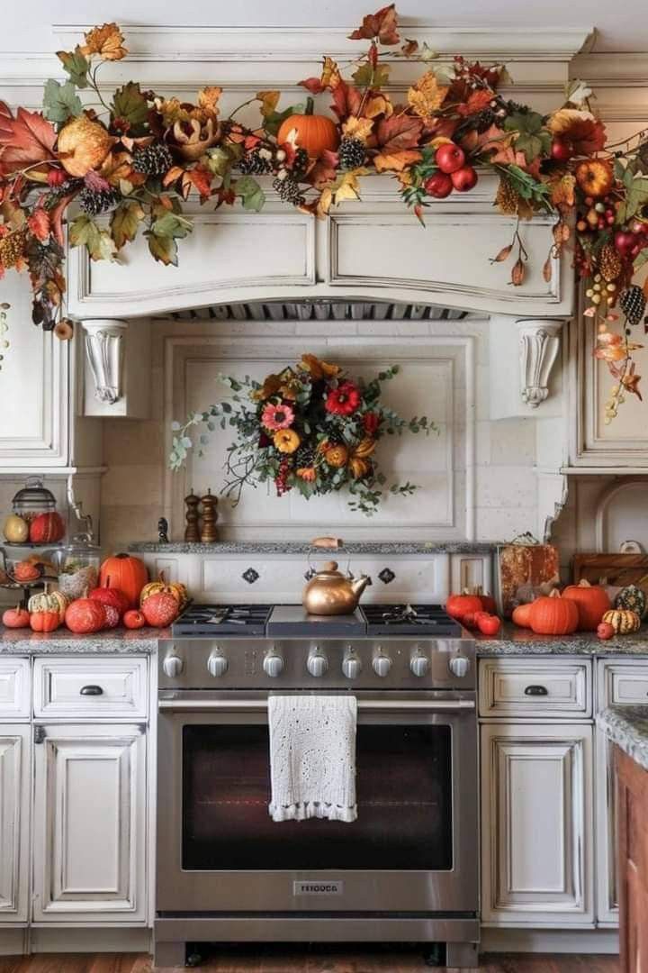 a kitchen decorated for fall with pumpkins and leaves on the stove top, along with other autumn decorations