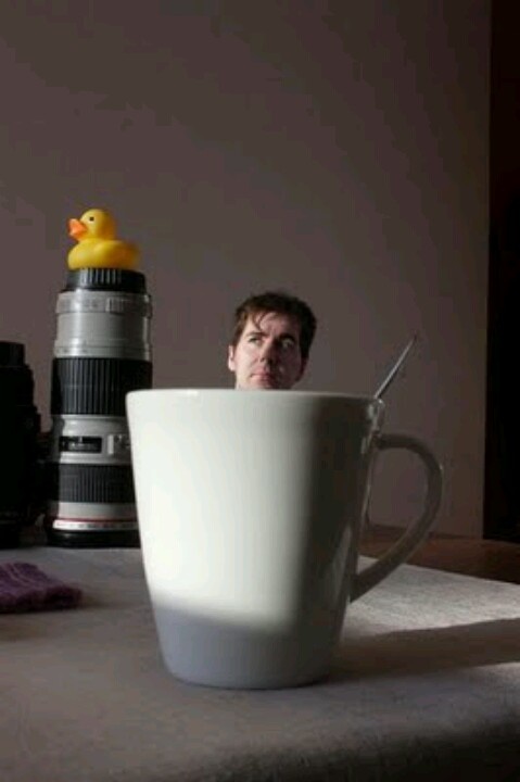 a man sitting in front of a coffee cup with a rubber duck on top