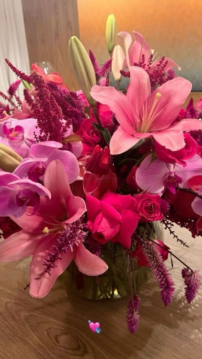 a vase filled with pink flowers on top of a wooden table