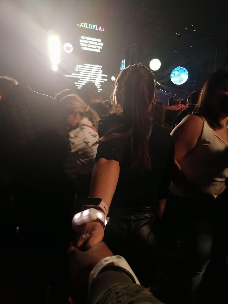 several people standing around in the dark with their hands on each other's hips