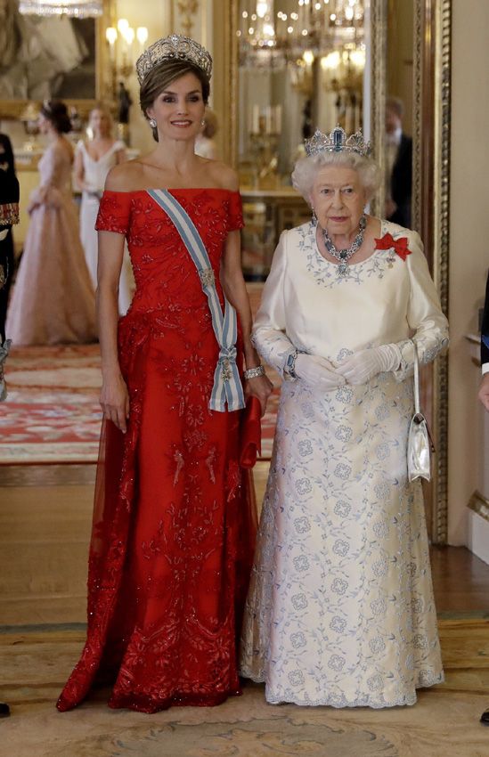 two women in red dresses and tiaras standing next to each other on the floor