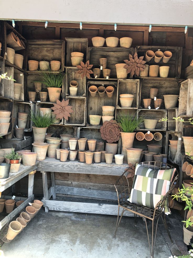 a room filled with lots of potted plants and wooden boxes on the wall next to a chair