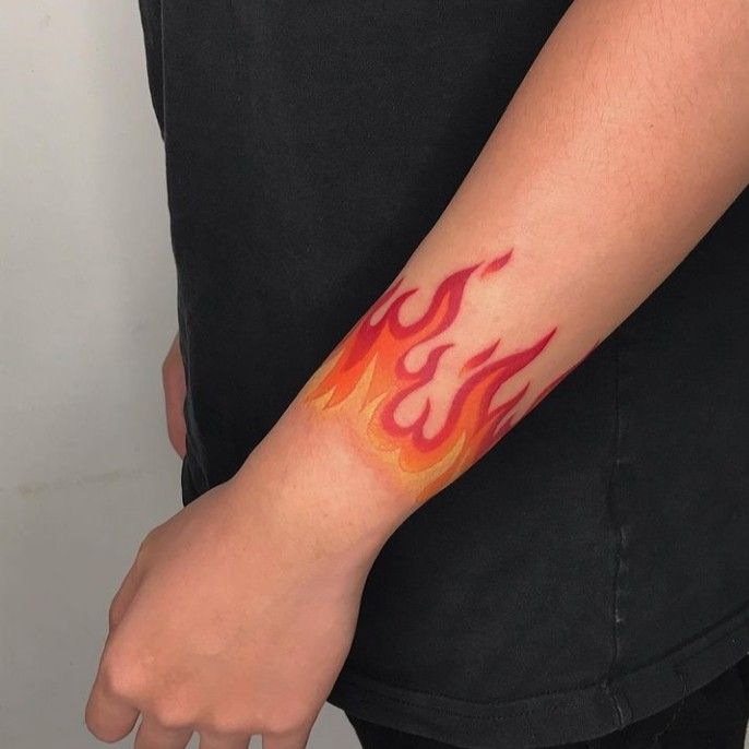 a man with a tattoo on his arm that has red and orange flames coming out of it