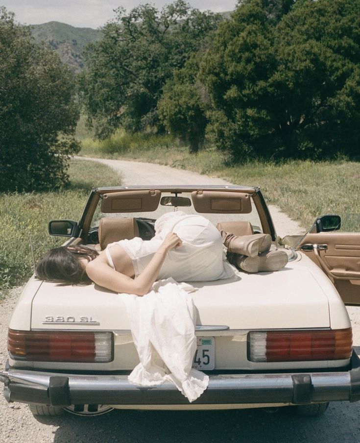 a woman laying on the back of a white car