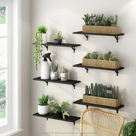 three black shelves with plants on them in a room next to a chair and window