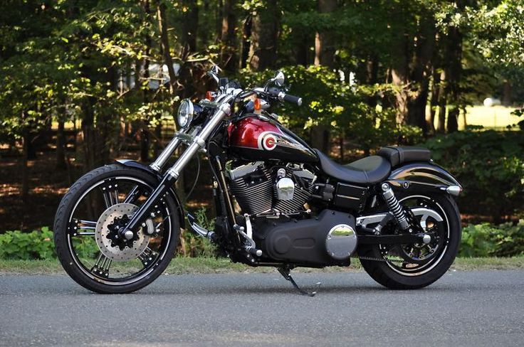 a red and black motorcycle parked on the side of the road in front of some trees