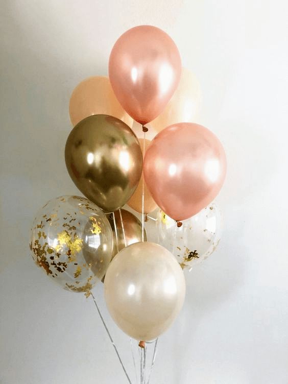 a bunch of balloons with gold and white confetti on them in a vase