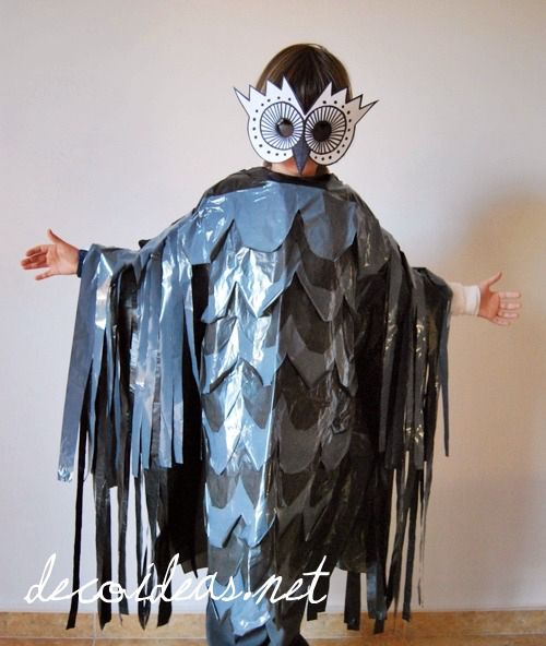 a child wearing a costume made out of duct tape and paper mache, standing in front of a white wall